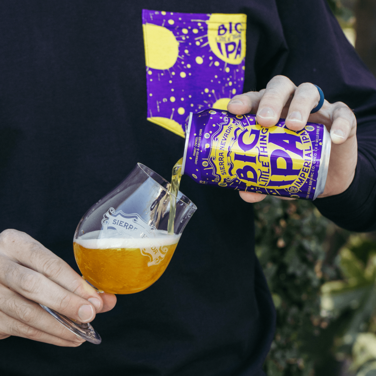 Man wearing a Big Little Thing shirt while pouring a can of Big Little Thing beer into a Sierra Nevada glass