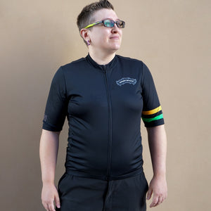 Thumbnail of Person wearing a black cycling outfit with colorful accents on a beige background