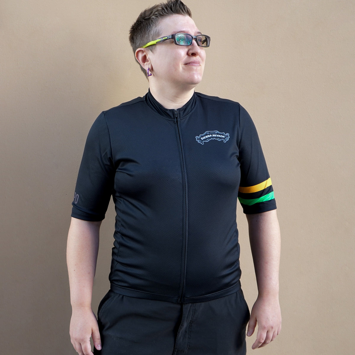 Person wearing a black cycling outfit with colorful accents on a beige background