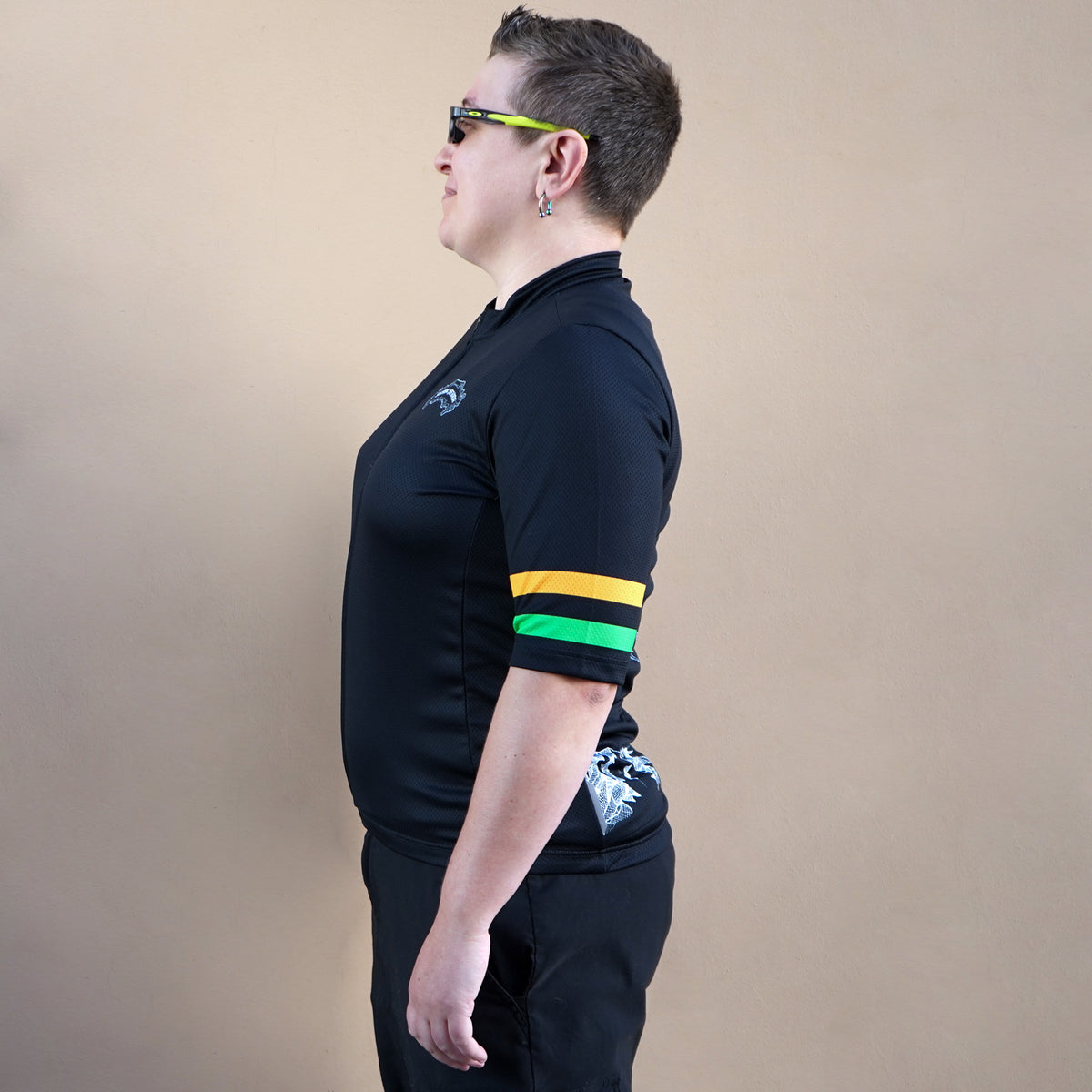 Person wearing a black cycling jersey with colorful stripes on a beige background
