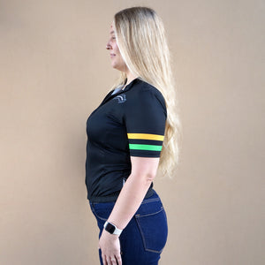 Thumbnail of Woman wearing a black polo shirt with colorful stripes on a beige background