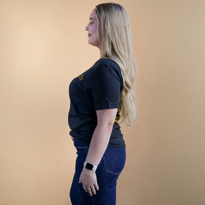 Thumbnail of Woman wearing a black t-shirt and blue jeans against a beige background