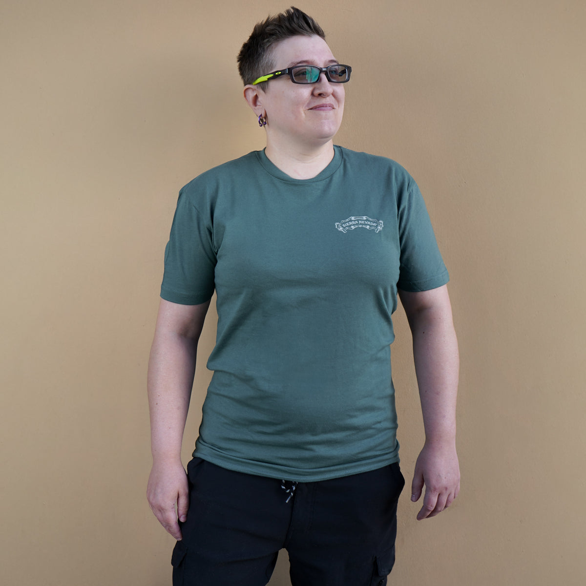 Person wearing a green t-shirt with a logo on a beige background