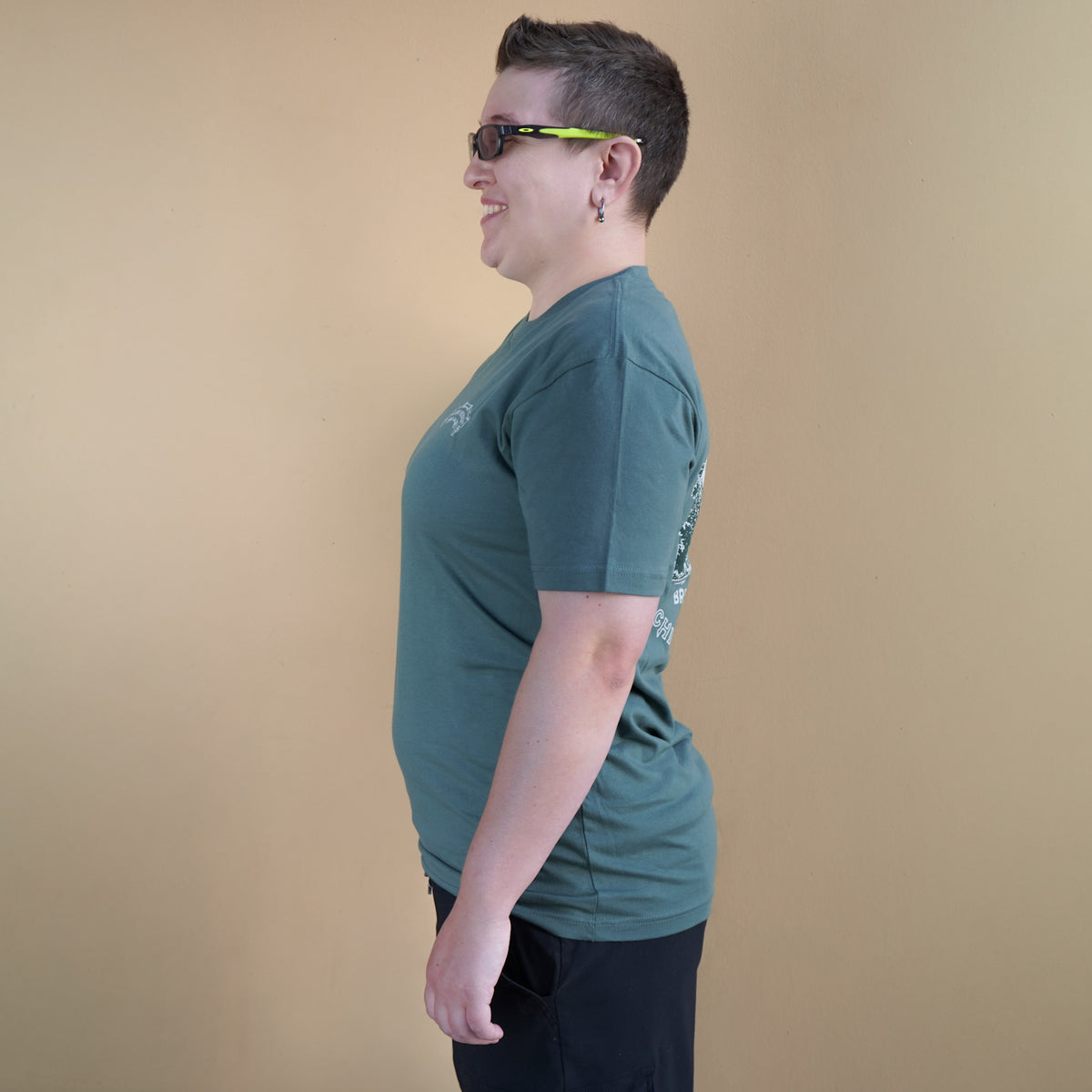 Person wearing a green t-shirt with a graphic design on a beige background