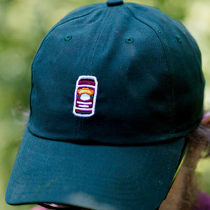 Thumbnail of Green cap with a logo worn by a person against a blurred green background