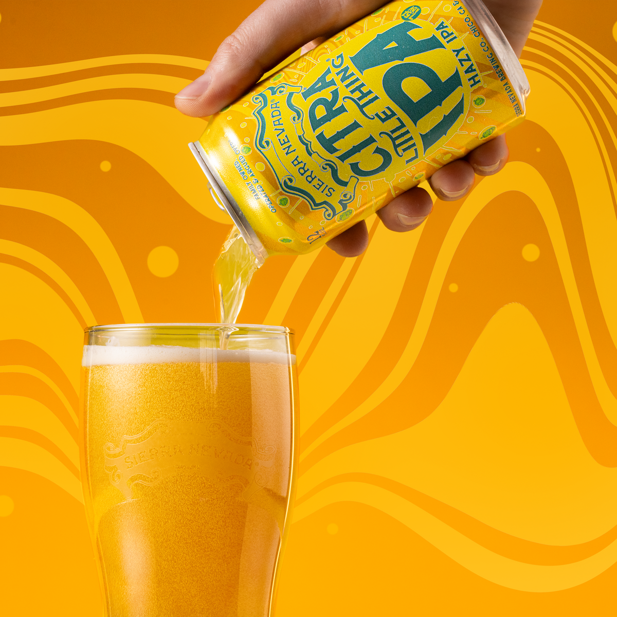 Hand pouring beer from a can into a glass against an orange background.