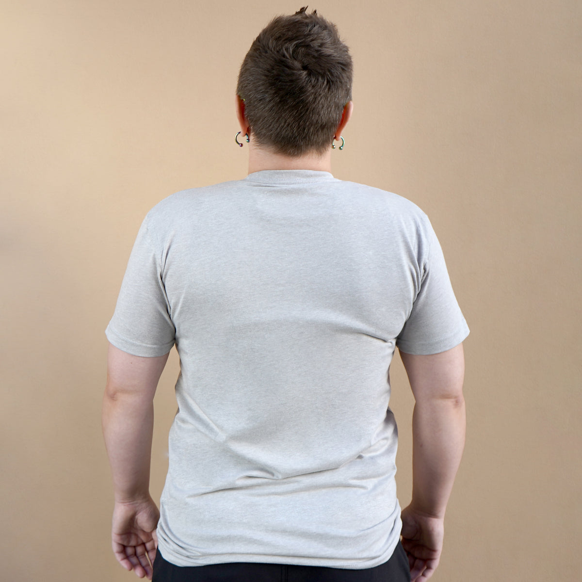 Person wearing a plain gray t-shirt against a beige background