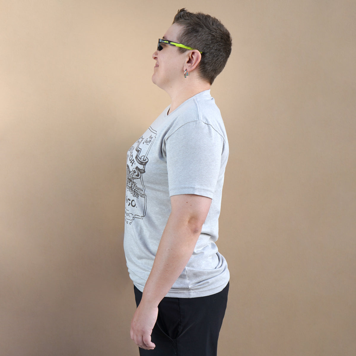 Person wearing a gray t-shirt with a graphic design on a beige background