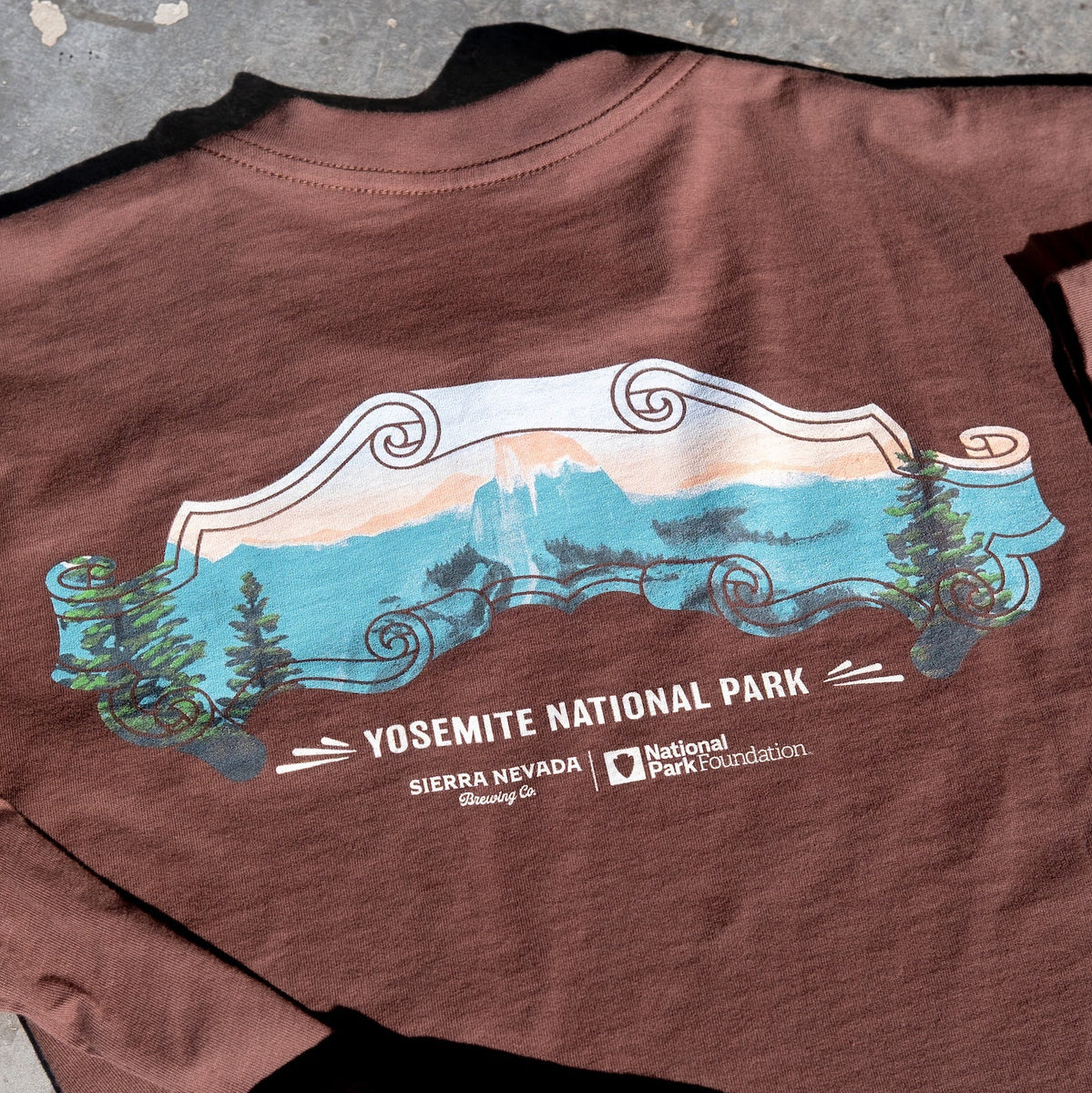 Brown t-shirt with Yosemite National Park graphic on a concrete surface
