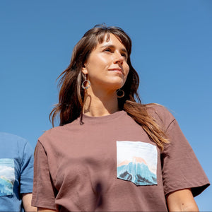 Thumbnail of Two people wearing t-shirts with mountain designs against a clear blue sky.