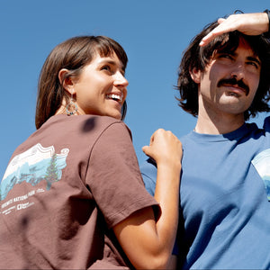 Thumbnail of Two people wearing t-shirts with nature-themed designs against a clear blue sky.