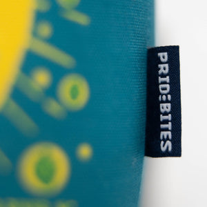Thumbnail of Close-up of a teal and yellow patterned fabric item with a black fabric tag on the right side featuring the white text 'PRIDEBITES'.