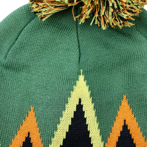 Thumbnail of Close-up of a green knit beanie with a multicolor geometric mountain pattern and a matching pom-pom on top.