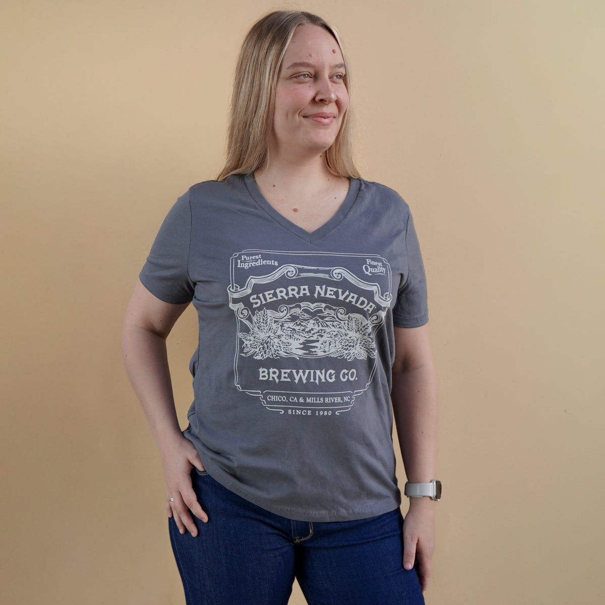Woman wearing a gray t-shirt with Sierra Nevada Brewing Co. logo against a beige background