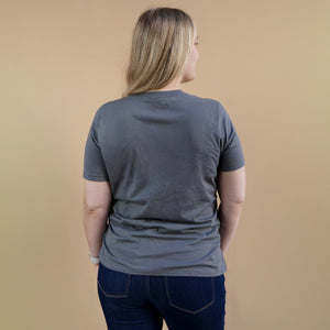 Thumbnail of Person wearing a gray t-shirt and dark jeans against a beige background