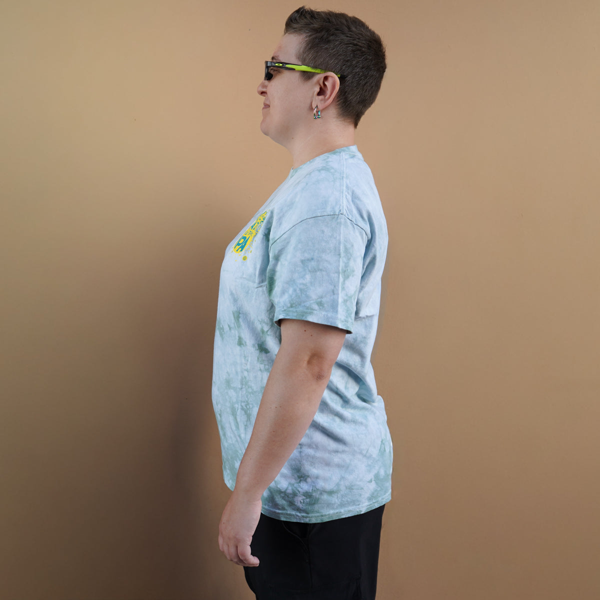 Person wearing a light blue tie-dye t-shirt against a brown background