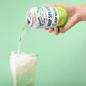 Thumbnail of Hand pouring a can of 'Hop Splash' non-alcoholic hop water into a glass against a green background