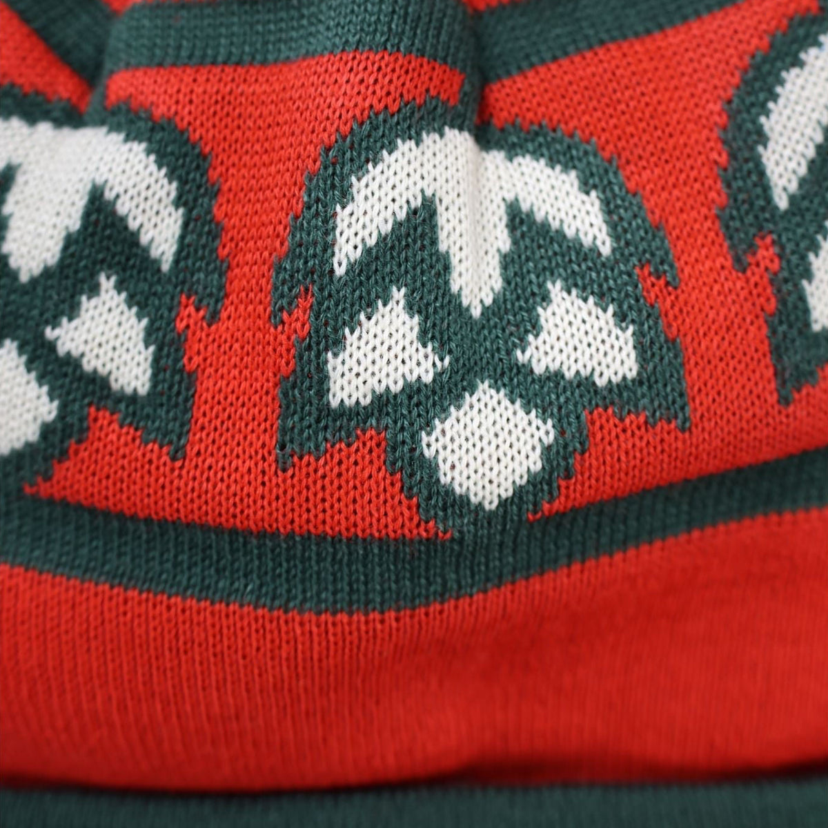 Red knitted hat with green and white patterns on a white background