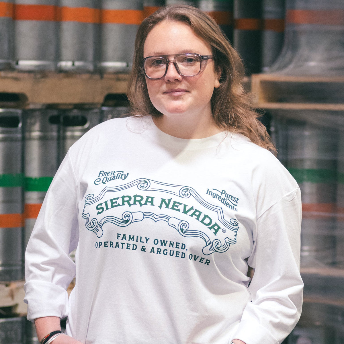 Person wearing a Sierra Nevada sweatshirt in front of beer barrels