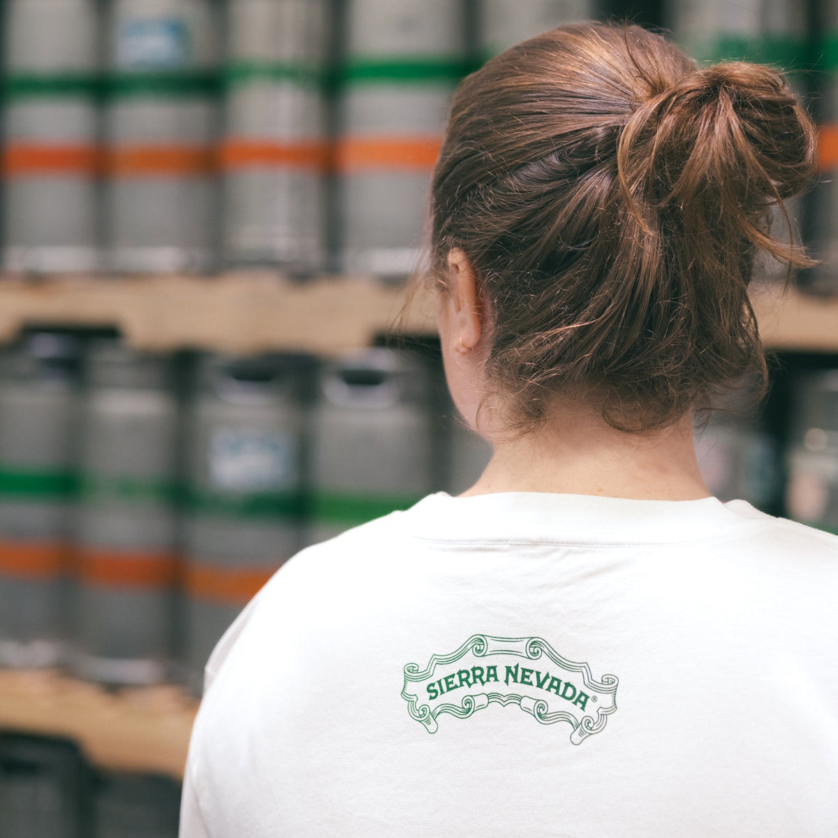 Person wearing a white shirt with 'Sierra Nevada' logo in a brewery setting