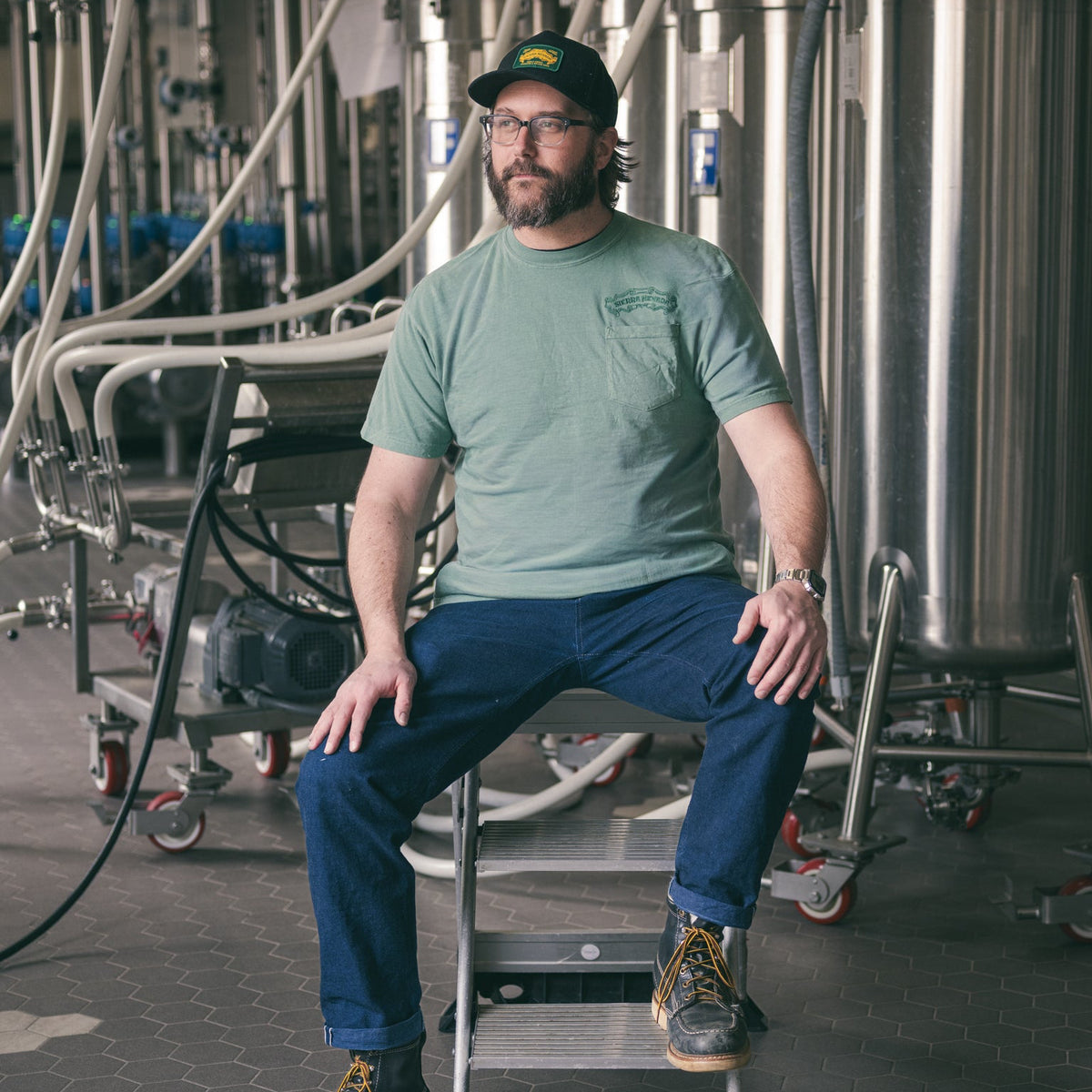 Man sitting on a ladder in a brewery setting