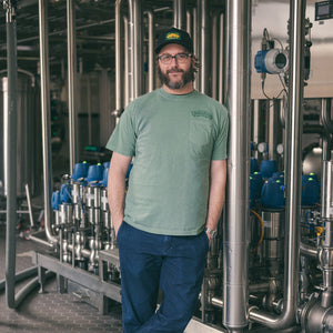 Thumbnail of Man standing in a brewery with industrial equipment