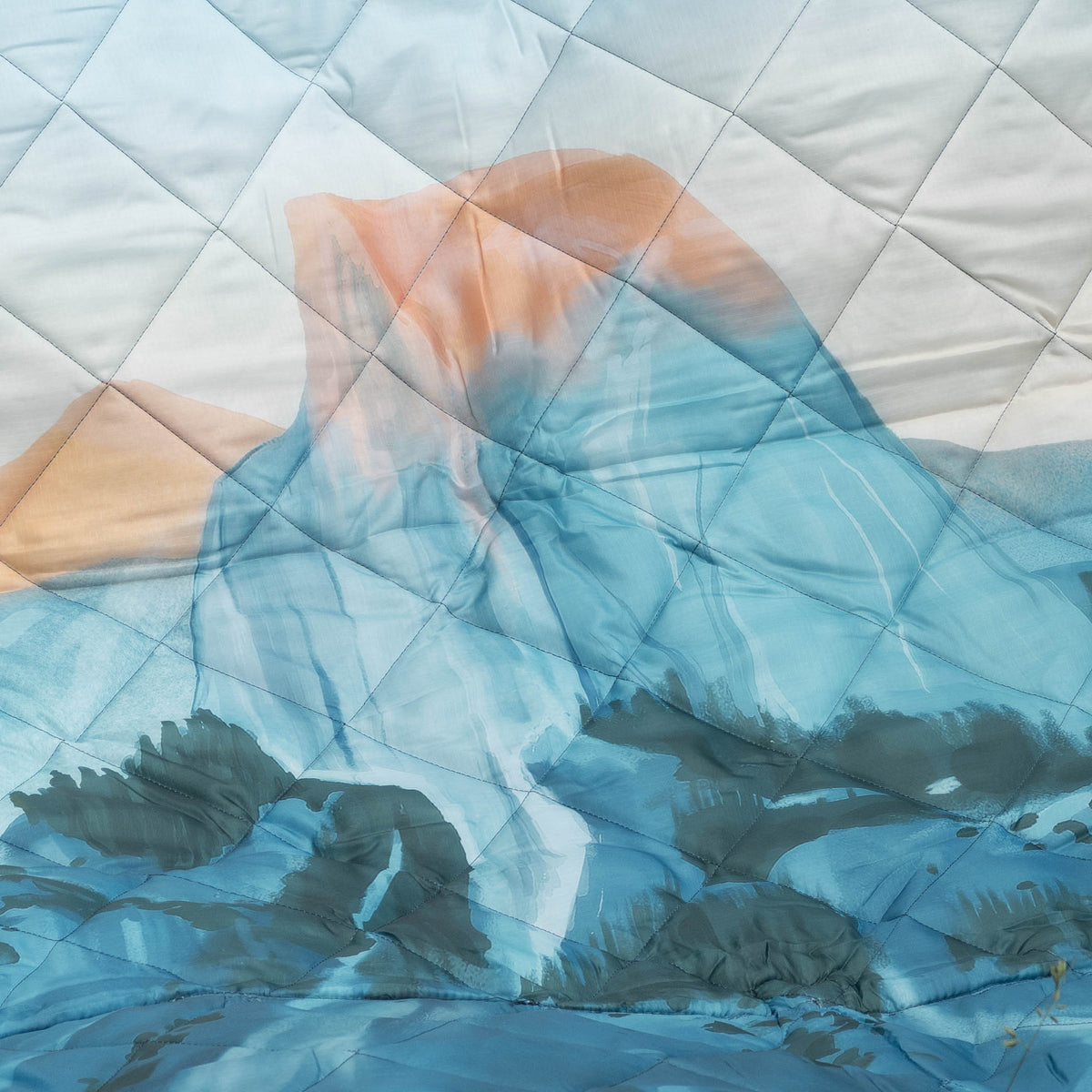 Quilt with a landscape design featuring mountains and water.