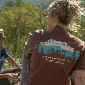 Thumbnail of Two people sitting on a log overlooking a forested area with Yosemite National Park t-shirt.