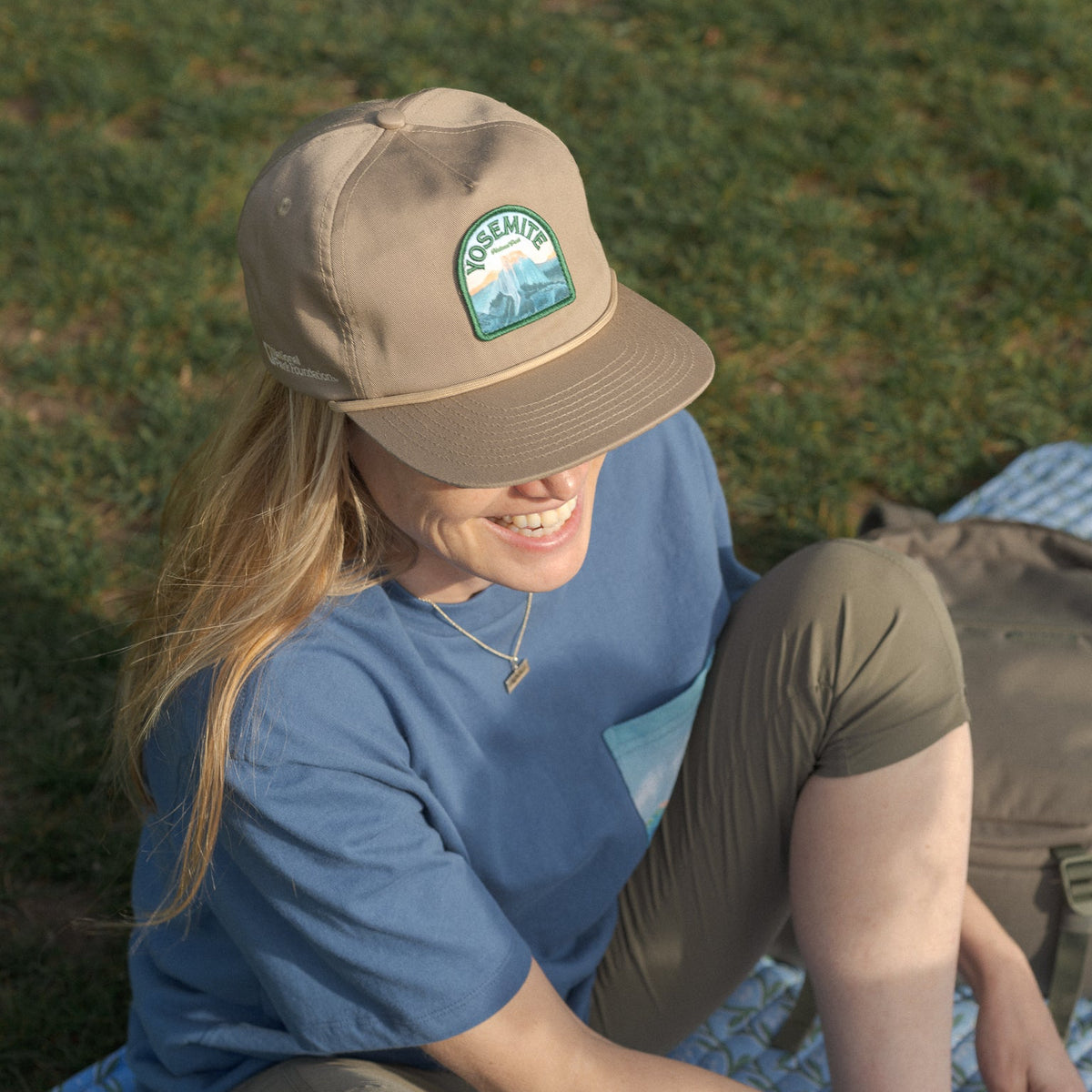 Person wearing a cap with a logo, sitting on a mat outdoors