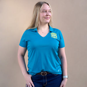 Thumbnail of Woman wearing a blue polo shirt with a logo on a beige background