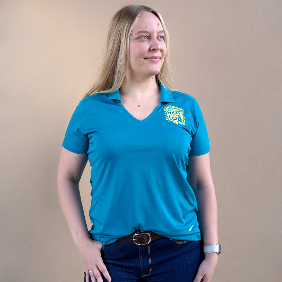 Woman wearing a blue polo shirt with a logo on a beige background