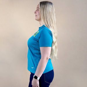 Thumbnail of Person wearing a blue shirt with a logo on a beige background