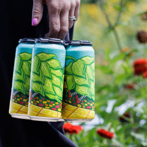 Thumbnail of Person holding a set of four beer cans with green and yellow designs, outdoors.