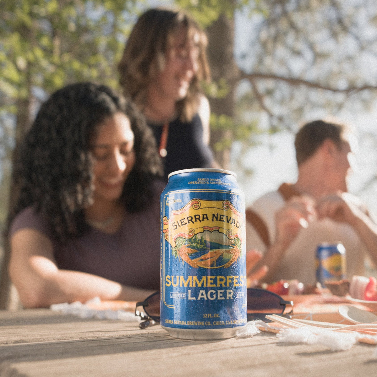 Can of Sierra Nevada Summer Lager on a picnic table with people in the background