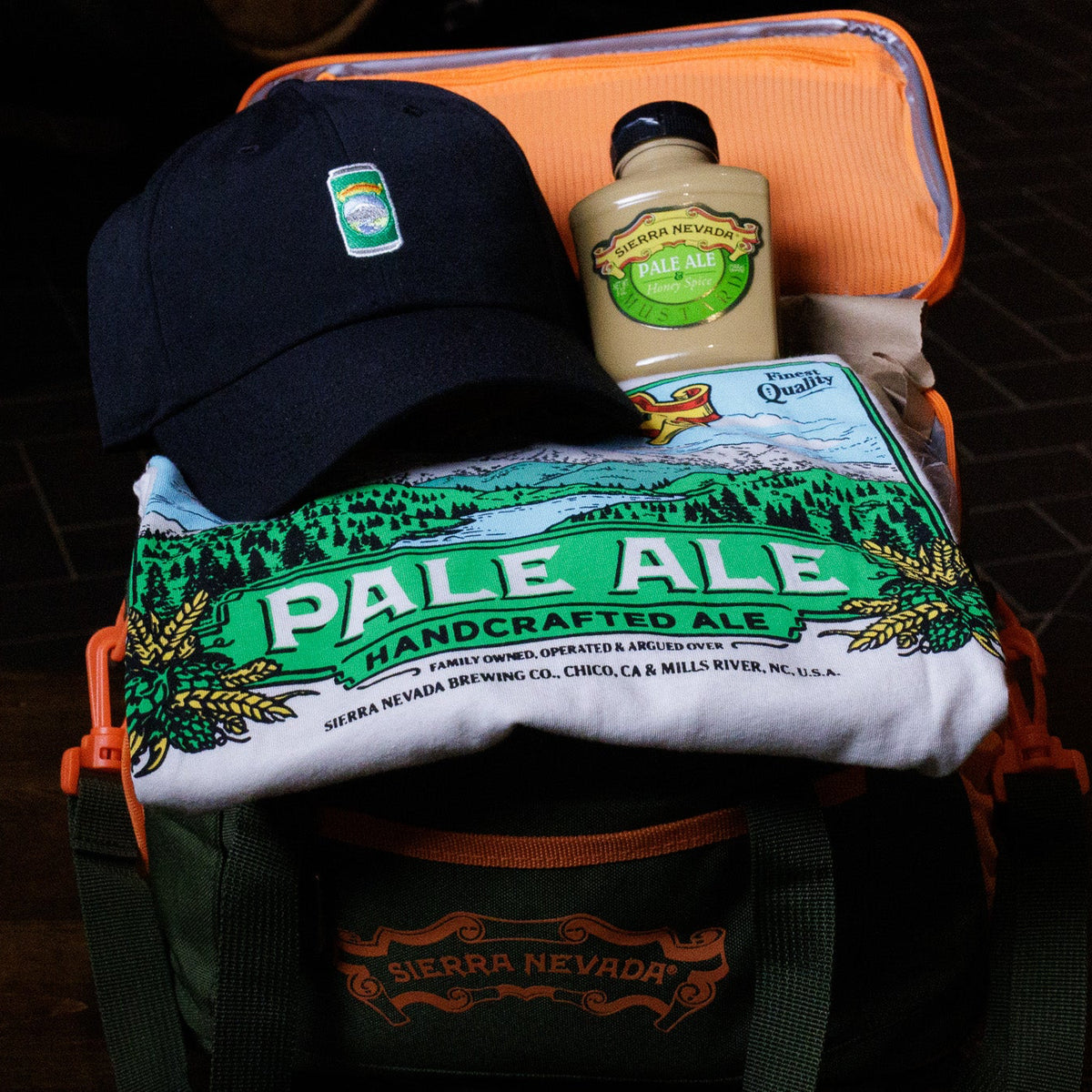 Cooler with a 'Pale Ale' t-shirt, bottle, and cap on a dark surface