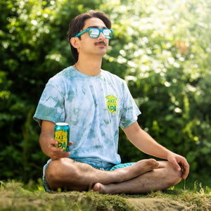 Thumbnail of Person sitting outdoors in a garden, holding a can of beer and wearing the Sierra Nevada Hazy Little Thing tie-dye t-shirt.