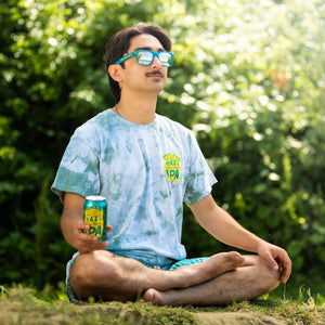Thumbnail of Person sitting outdoors in a garden, holding a can of beer.