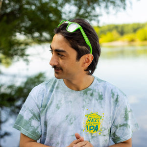 Thumbnail of Man wearing a tie-dye shirt with a logo by a lake