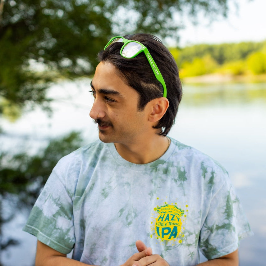 Man wearing a tie-dye shirt with a logo by a lake