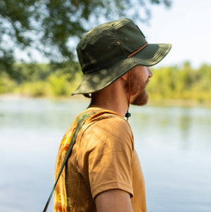 Thumbnail of Man with a green and orange bag by a lake