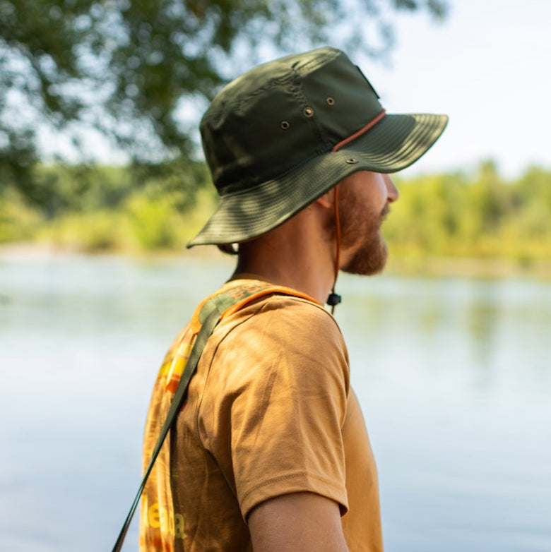 Man with a green and orange bag by a lake