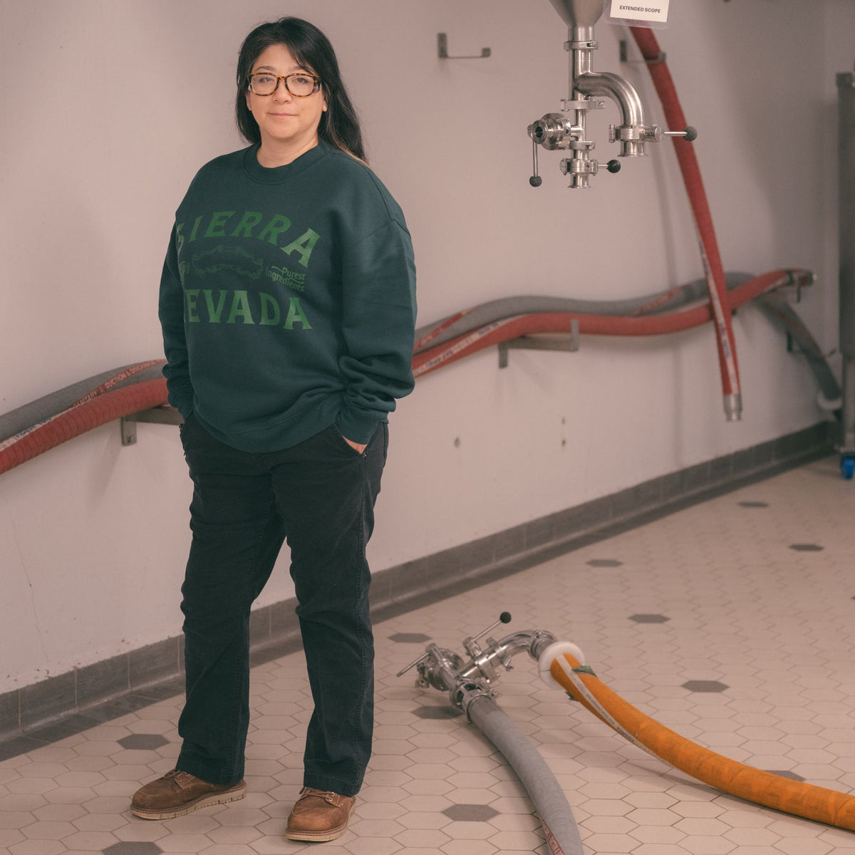 Person wearing a green sweatshirt with 'Sierra Nevada' text in an industrial setting.