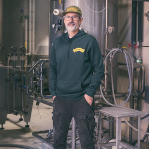 Thumbnail of Person wearing a green hoodie with a logo in an industrial setting