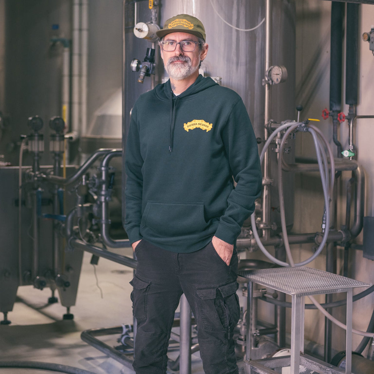 Person wearing a green hoodie with a logo in an industrial setting