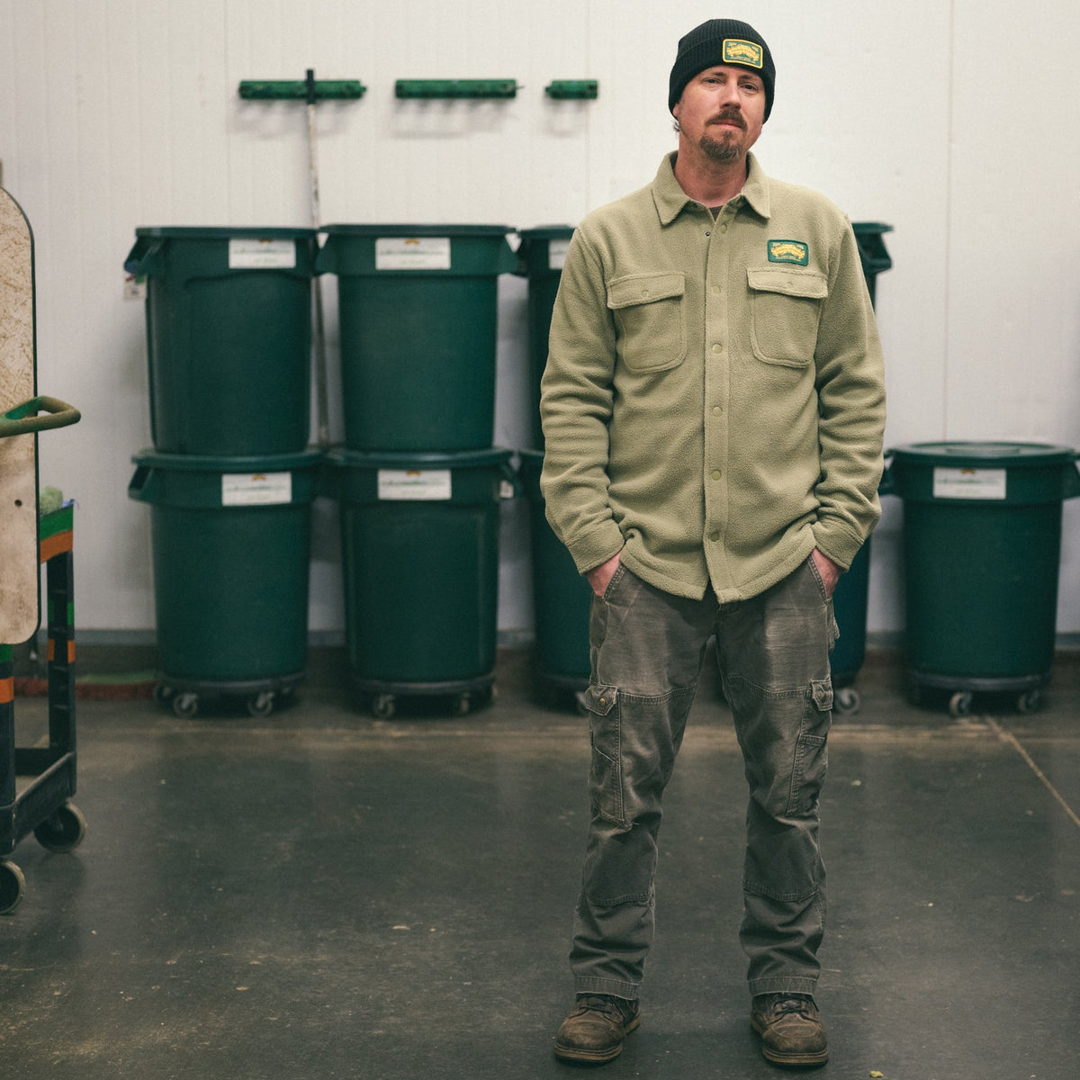Man standing in a room with green bins and a white wall
