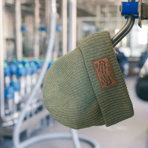 Thumbnail of Green beanie with a brand logo on a metal bar in a brewing setting