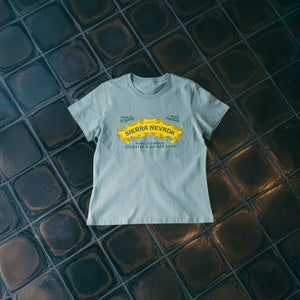 Thumbnail of Light gray t-shirt with yellow graphic on a dark tiled floor