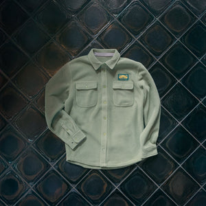 Thumbnail of Light green shirt with a patch on a dark tiled wall