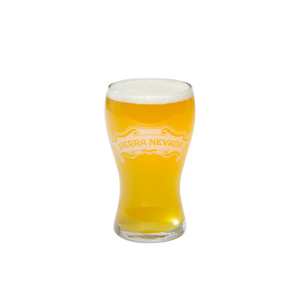 Thumbnail of A clear glass pint glass filled with golden beer and topped with white foam, featuring the 'Sierra Nevada' logo printed in gold on the front, isolated on a white background.