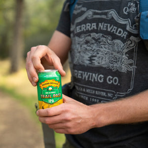 Thumbnail of Sierra Nevada Brewing Co. Trail Pass IPA Non-Alcoholic Brew - A hiker pauses to crack open a can of Trail Pass IPA